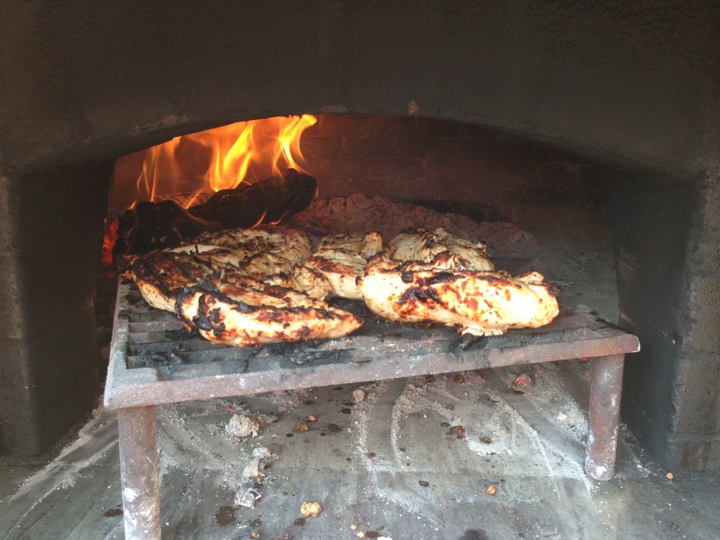 wood-fired grilling chicken in a wood-burning oven